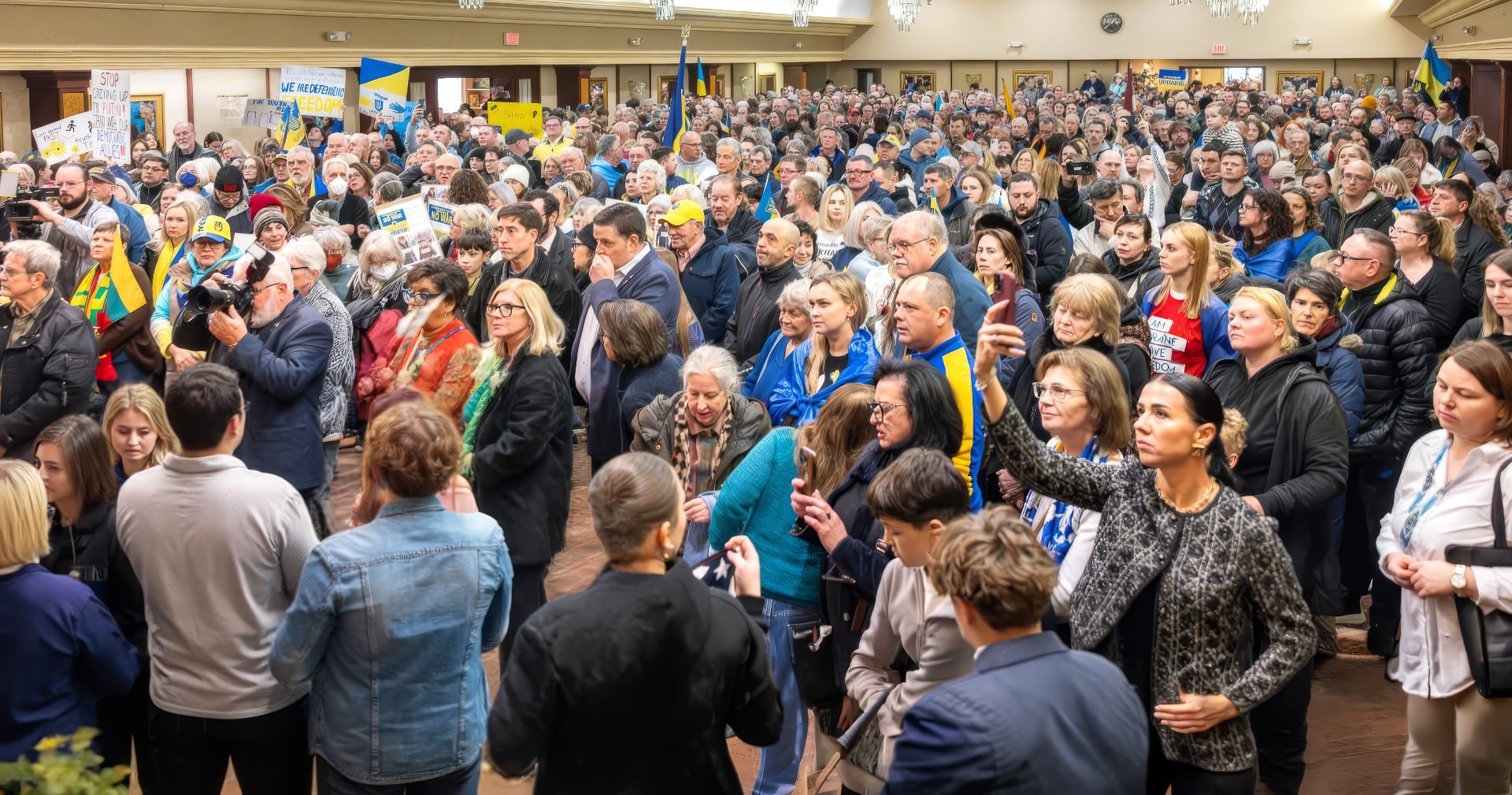 A packed hall of community members standing together with Ukrainian flags and signs at a Cleveland Maidan gathering